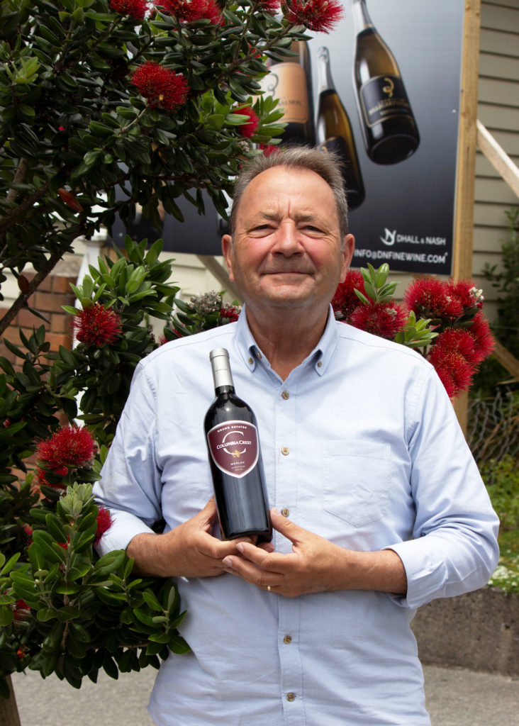 Man holding wine bottle under Pohutukawa tree